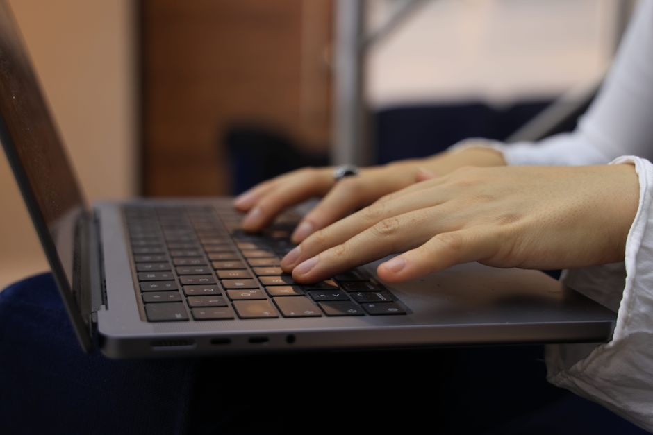 Person's hands resting on a laptop keyboard, suggesting repetitive wrist strain