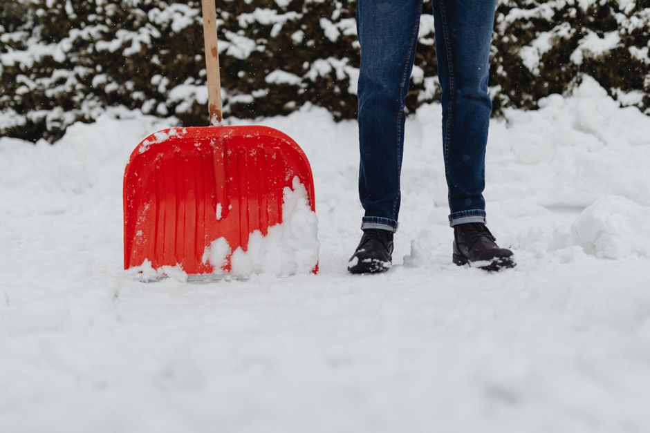 A snow shovel resting on a freshly cleared driveway after a winter snowfall