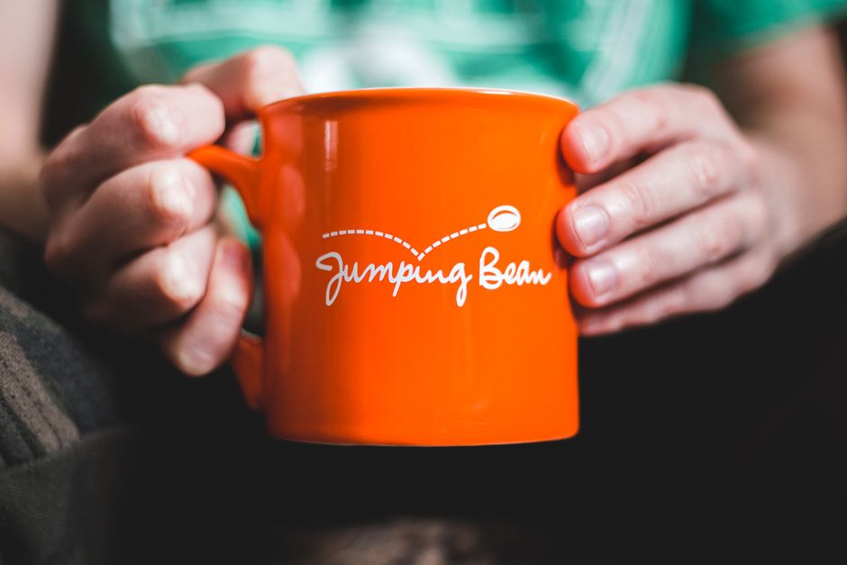 Two hands wrapped around a warm mug on a cold morning, fingers slightly stiff